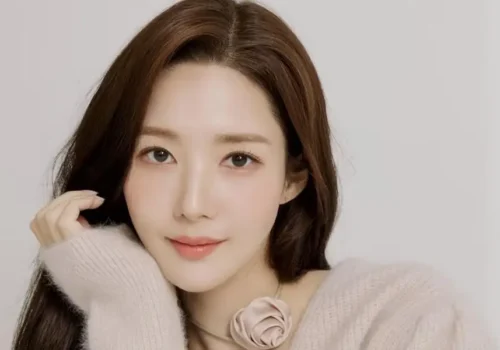 Park Min Young souriante lors d’un événement promotionnel, vêtue d’une tenue élégante, incarnant son nouveau rôle audacieux dans The Confidence Man KR.